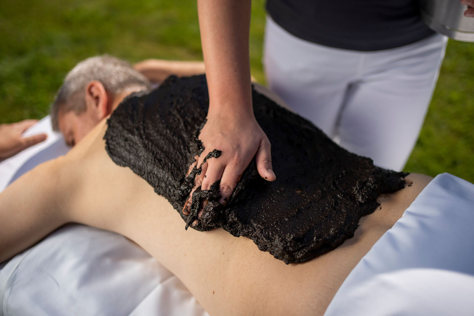 Gast entspannt bei einer wirkungsvollen Moorpackung am Rücken um seine Rückenschmerzen zu behandeln